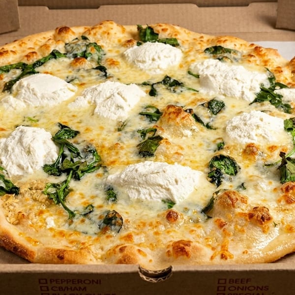 A white pizza with spinach and dollops of ricotta cheese in a cardboard delivery box.
